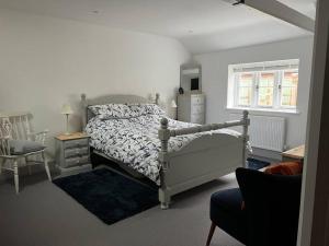 a bedroom with a bed and a chair and a window at idyllic rural retreat - stunning 2 bed annex. in Wood Norton