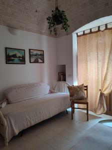 een slaapkamer met een bed, een stoel en een raam bij B&B Aquila in Alberobello