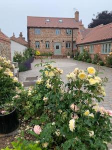 a garden with roses in front of a house at idyllic rural retreat - stunning 2 bed annex. in Wood Norton