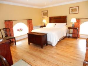 a bedroom with a white bed and two windows at The Courtyard Kilshannig in Fermoy