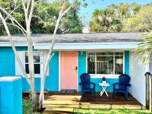 a blue and white house with a pink door and two chairs at Beach Bungalow in downtown Cocoa Beach in Cocoa Beach