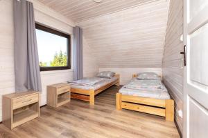 zwei Betten in einem Zimmer mit Fenster in der Unterkunft MarkoweDomki,pl in Jantar