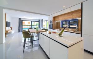 a kitchen with white cabinets and a bar with stools at Apartment Rosa in Malinska