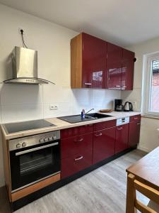 a kitchen with red cabinets and a sink at Oberhausen Apartments in Oberhausen