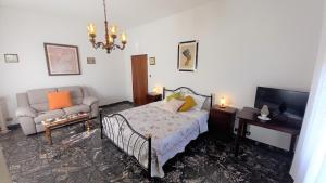 1 dormitorio con cama, sofá y TV en OPERA21 TUSCANY SINGLE HOUSE LUCIGNANO, en Lucignano