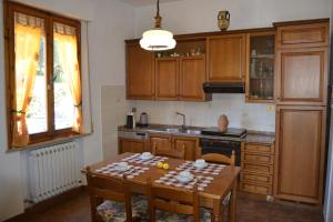 una cocina con armarios de madera y una mesa con sillas. en OPERA21 TUSCANY SINGLE HOUSE LUCIGNANO, en Lucignano