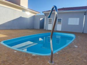 a blue swimming pool in front of a house at Casa Lazer com piscina in Brotas