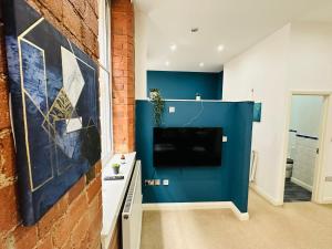 a living room with a blue wall and a tv at Lovely Studio Apartment in the Heart of Nottingham in Nottingham