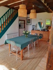 ein Esszimmer mit einem grünen Tisch und Stühlen in der Unterkunft La Ferme Neuve in Fillé
