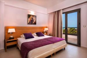 a hotel room with a bed and a window at Porto Platanias Village Resort in Plataniás
