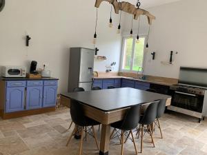 una cucina con armadi blu, tavolo e sedie di Gîte La Grange Maison entière a Blicourt