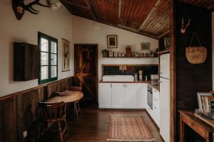 una cocina con armarios blancos y una mesa. en La ferme du pont de Maumy, cabane au bord de l'étang et bain nordique, en Busserolles