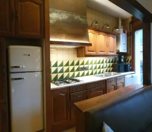 eine Küche mit einem weißen Kühlschrank und Holzschränken in der Unterkunft Casa Matilda - Apartamento con chimenea, vistas, rustico-elegante en el centro in Sant Joan de les Abadesses