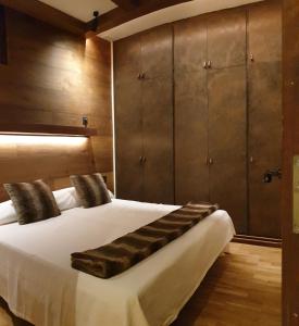 1 dormitorio con 1 cama blanca grande y paredes de madera en Casa Matilda - Apartamento con chimenea, vistas, rustico-elegante en el centro, en Sant Joan de les Abadesses