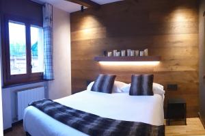 Schlafzimmer mit einem Bett mit weißer Bettwäsche und schwarzen Kissen in der Unterkunft Casa Matilda - Apartamento con chimenea, vistas, rustico-elegante en el centro in Sant Joan de les Abadesses