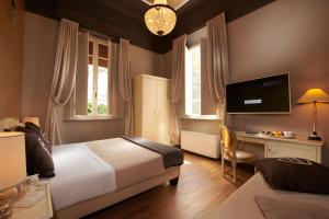 a bedroom with two beds and a desk and a television at Villa Tower Inn in Pisa