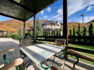 a table and chairs on a porch with a view of a house at PLANINSKO JUTRO - Brzeće Centar Apartments, Kopaonik in Brzeće