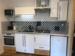 Eine Küche mit weißen Schränken, Spüle und Herd in der Unterkunft Une terrasse à L’Estaque + stationnement in Marseille