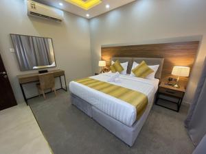 a hotel room with a large bed and a desk at Vital House Apartments شقق البيت الحيوي in Jeddah