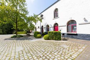a brick courtyard in front of a white building at Domein Tombos in Gingelom
