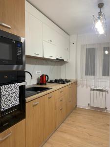 a kitchen with white cabinets and a black microwave at Sunny Apartment in Suceava in Suceava