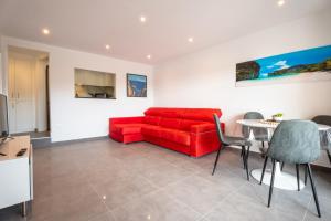 een woonkamer met een rode bank en een tafel bij Apartamento California Almadrava in Montjoys