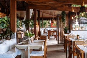 a restaurant with wooden tables and chairs and plants at Vila Dos Orixás Boutique Hotel in Morro de São Paulo