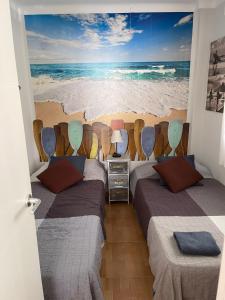 2 łóżka w pokoju z malowidłem plażowym w obiekcie Apartamento Ivon Solo Familias w mieście Playa de Gandia