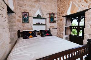 Un dormitorio con una cama en una pared de piedra. en نزل كوفان التراثي Koofan Heritage Lodge, en Salalah