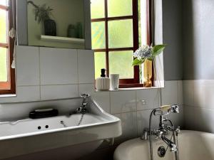 a bathroom with a tub and a sink and a window at Comfy Greyton Cottage for Four in Greyton