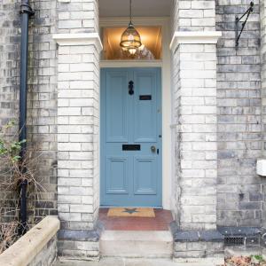 a blue door on a brick house with a light fixture at 35 Grosvenor Terrace - 5 min walk from York City Centre in York