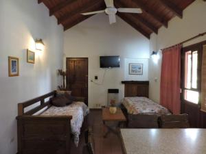 1 dormitorio con 2 camas, mesa y ventilador de techo en Cabañas de la Colina en Villa General Belgrano