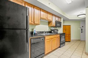 uma cozinha com um frigorífico preto e armários de madeira em The Splendid South Carolina Getaway em Myrtle Beach