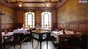 un restaurante con mesas y sillas blancas y ventanas en Weinhaus Wöhler, en Schwerin