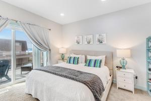 a white bedroom with a bed and a balcony at EazyBreezy in Rockaway Beach