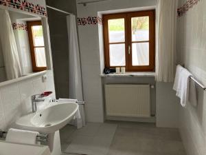 a white bathroom with a sink and a mirror at Watzmannkar in Bischofswiesen