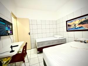 a room with two beds and a sink and a tv at 202 Kitnet no centro com wifi in Aracaju