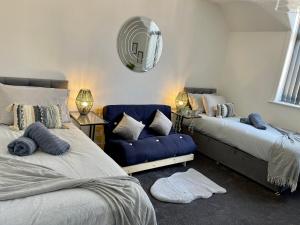 a bedroom with two beds and a blue couch at Casa Lobo's Beautiful Suites Apartment 1 free offroad parking in Fallings Park