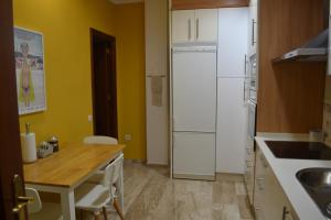 a kitchen with a table and a white refrigerator at Apartamento Posidonia Free Parking in Cádiz