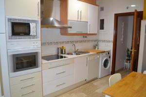 cocina con armarios blancos, fregadero y microondas en Apartamento Posidonia Free Parking, en Cádiz