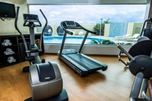 a gym with exercise bikes and a swimming pool at Lidotel Barquisimeto in Barquisimito