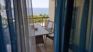 een balkon met een tafel en stoelen en uitzicht op de oceaan bij THE VIEW APARTMENT KAVALA in Kavala