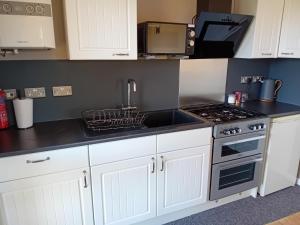 a kitchen with white cabinets and a stove top oven at Love Nest in Deal