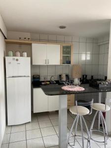 uma cozinha com um frigorífico branco, uma mesa e cadeiras em Apartamento Ponta Negra em Natal