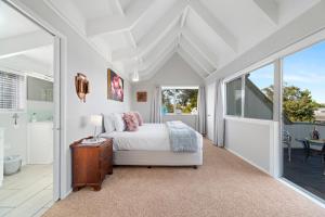 a white bedroom with a bed and a bathroom at Botanical HideAway Taupo in Taupo