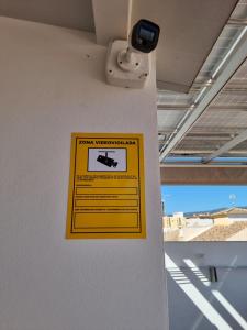 a yellow sign on the side of a wall at APARTAMENTOS ELEMAR free luggage storage in Málaga