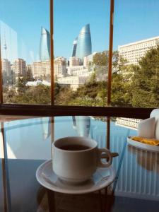 a cup of coffee sitting on a table in front of a window at City Walls Hotel in Baku