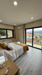 ein Schlafzimmer mit einem großen Bett und großen Fenstern in der Unterkunft Casa da Falperra in Arcos de Valdevez