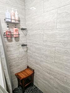 a shower with white tiled walls and a wooden stool at Cozy and Renovated 3 Bedroom Home 