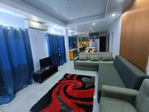 a living room with two couches and a living room with blue curtains at Pacific Apartment in Suva